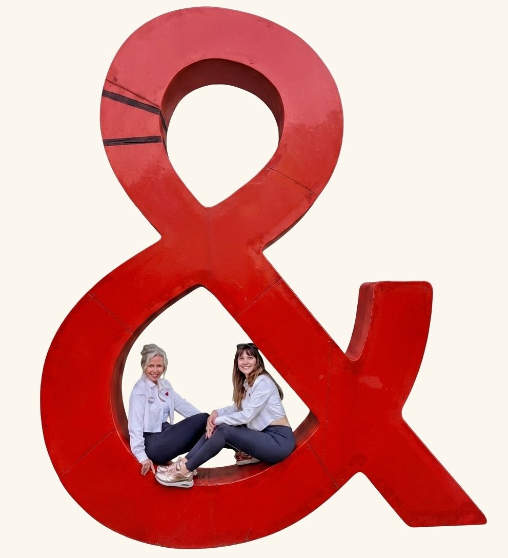 Kathleen und Anne sitzen gemeinsam in einem großen roten Und-Zeichen